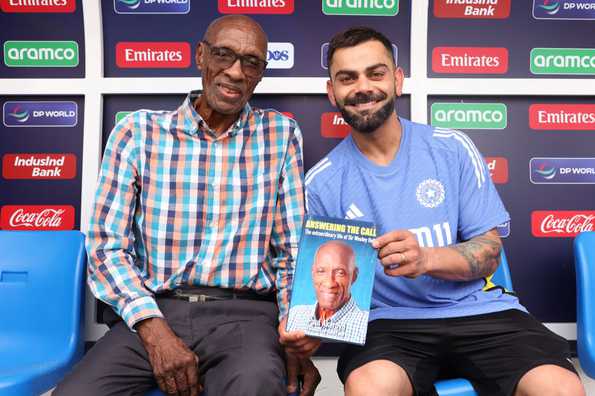 Virat Kohli poses with Sir Wesley Hall after receiving a copy of his book. Virat Kohli poses with Sir Wesley Hall after receiving a copy of his book.